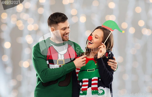 Image of couple with christmas party props in ugly sweaters