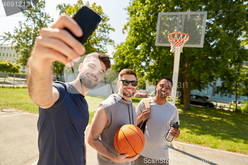 Image of happy men taking selfie on basketball playground