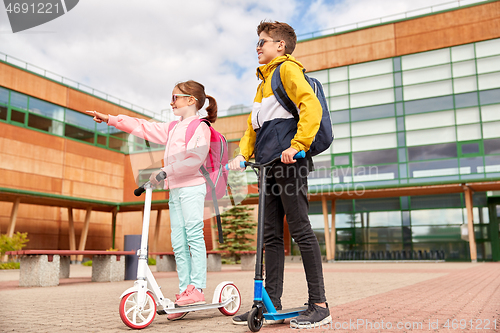 Image of happy school children with backpacks and scooters