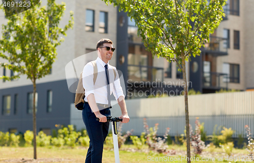 Image of businessman with backpack riding electric scooter