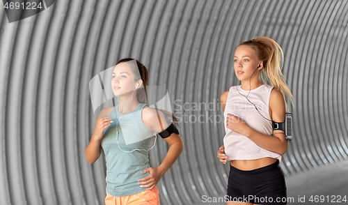 Image of young women with earphones and smartphones running