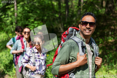 Image of group of friends with backpacks hiking in forest