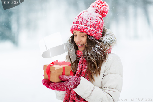 Image of happy young woman with christmas gift in winter