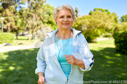 Image of senior woman with earphones running at summer park
