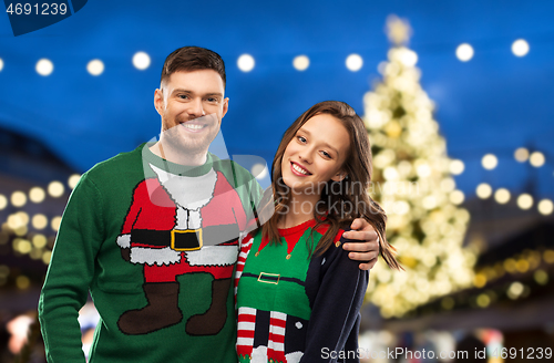 Image of happy couple in ugly sweaters at christmas market