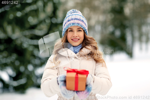 Image of happy young woman with christmas gift in winter