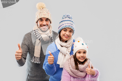 Image of happy family in winter clothes on grey background