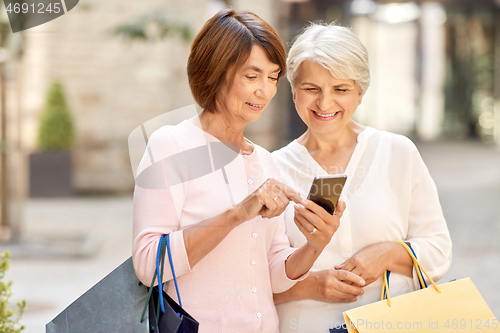 Image of old women with shopping bags and cellphone in city