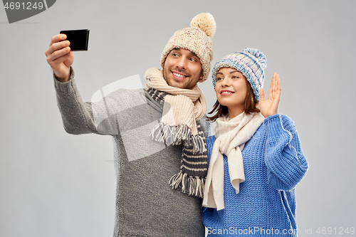 Image of couple in winter hats taking selfie by smartphone