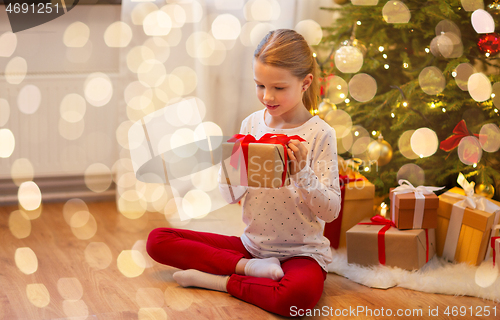Image of smiling girl with christmas gift at home