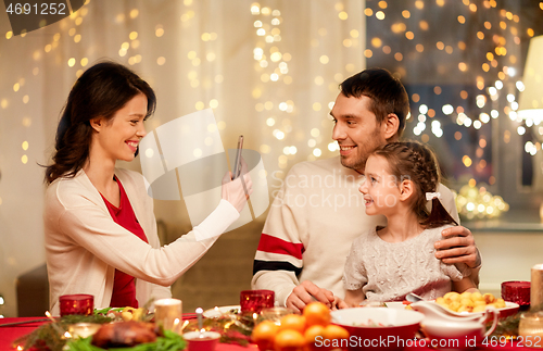 Image of happy family taking picture at christmas dinner