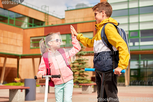 Image of happy school children with backpacks and scooters