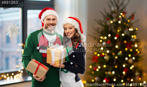 Image of happy couple in sweaters with christmas gifts