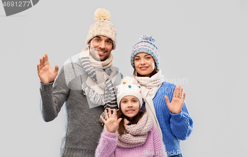 Image of happy family in winter clothes waving hands