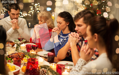 Image of friends having home christmas dinner and praying
