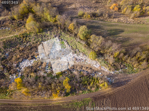 Image of Aerial view from drone above dumpsite surrounded by trees.