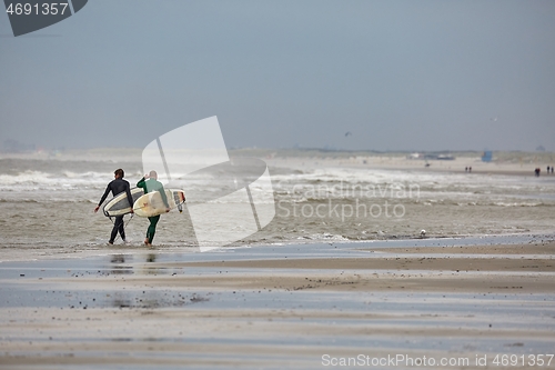 Image of Surfers entering the water in cold windy weather