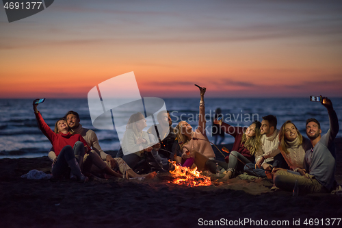 Image of a group of friends enjoying bonfire on beach