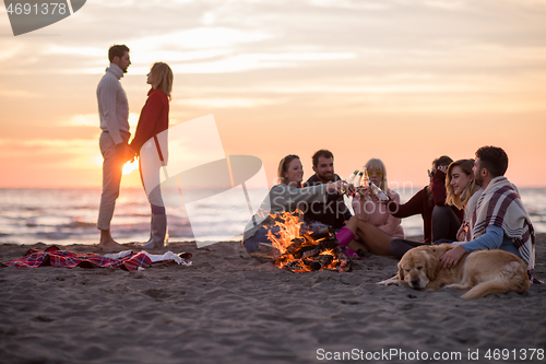 Image of Couple enjoying with friends at sunset on the beach