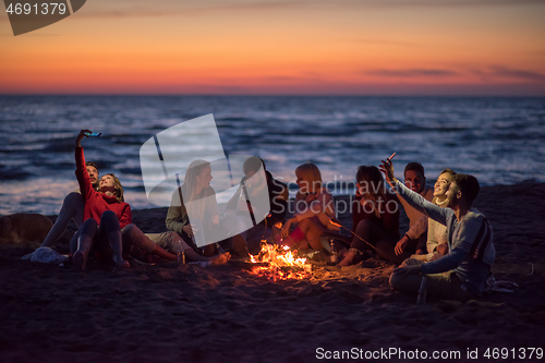 Image of a group of friends enjoying bonfire on beach