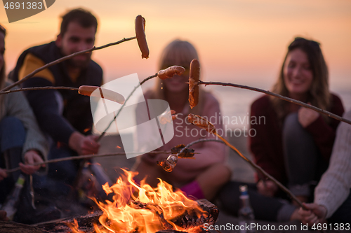 Image of Group Of Young Friends Sitting By The Fire at beach