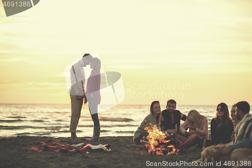 Image of Couple enjoying with friends at sunset on the beach