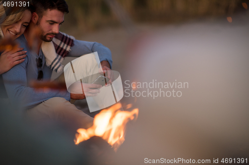 Image of Group Of Young Friends Sitting By The Fire at beach