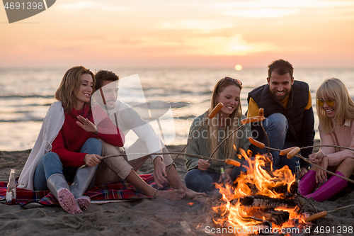 Image of Group Of Young Friends Sitting By The Fire at beach