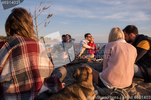 Image of Couple enjoying with friends at sunset on the beach