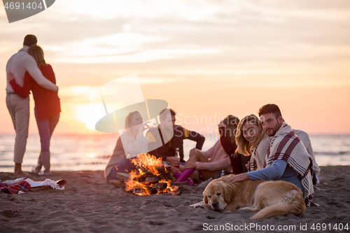 Image of Couple enjoying with friends at sunset on the beach