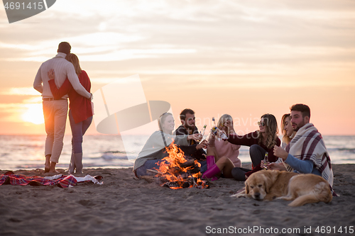 Image of Couple enjoying with friends at sunset on the beach