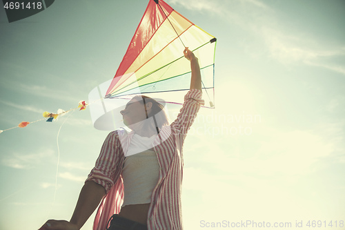 Image of Young Woman with kite at beach on autumn day