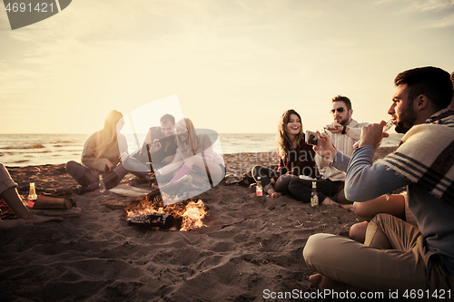 Image of Friends having fun at beach on autumn day