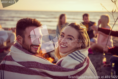 Image of Couple enjoying with friends at sunset on the beach