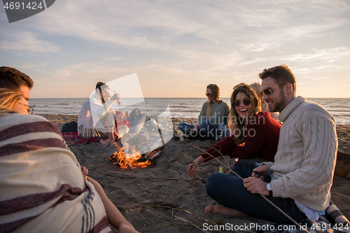 Image of Couple enjoying with friends at sunset on the beach