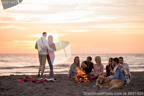 Image of Couple enjoying with friends at sunset on the beach