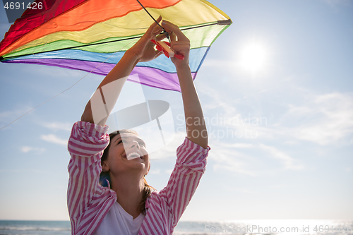 Image of Young Woman with kite at beach on autumn day