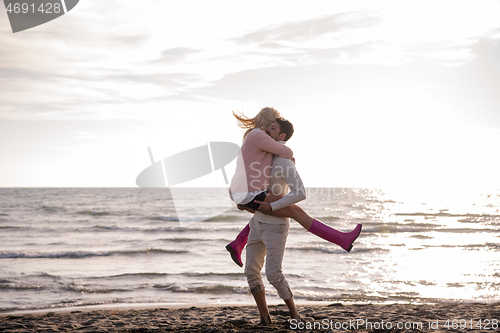 Image of Loving young couple on a beach at autumn sunny day