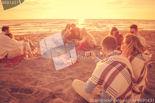 Image of Friends having fun at beach on autumn day