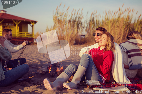 Image of Couple enjoying with friends at sunset on the beach