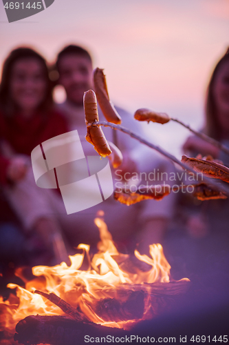 Image of Group Of Young Friends Sitting By The Fire at beach