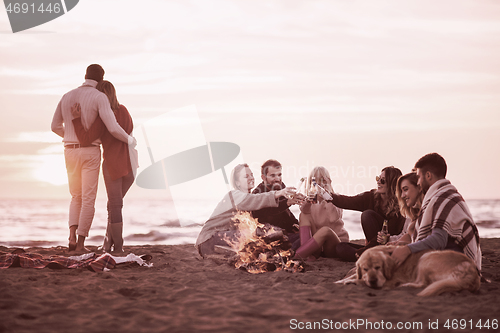 Image of Couple enjoying with friends at sunset on the beach