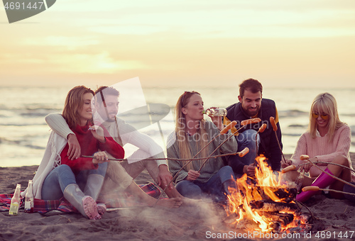 Image of Group Of Young Friends Sitting By The Fire at beach