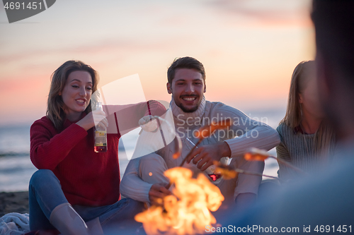 Image of Group Of Young Friends Sitting By The Fire at beach