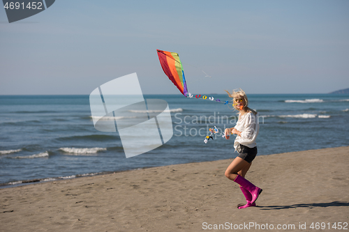 Image of Young Woman with kite at beach on autumn day