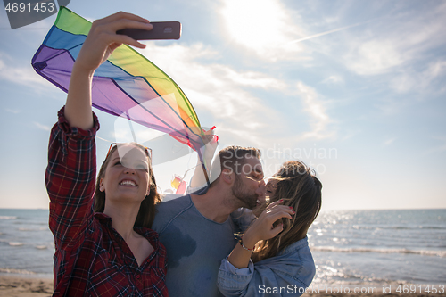 Image of Group of friends making selfie on beach during autumn day