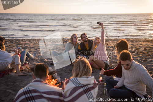 Image of Friends having fun at beach on autumn day