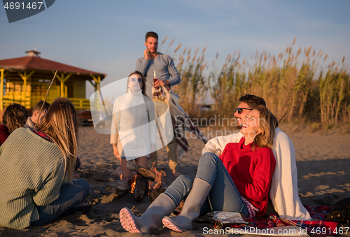 Image of Couple enjoying with friends at sunset on the beach