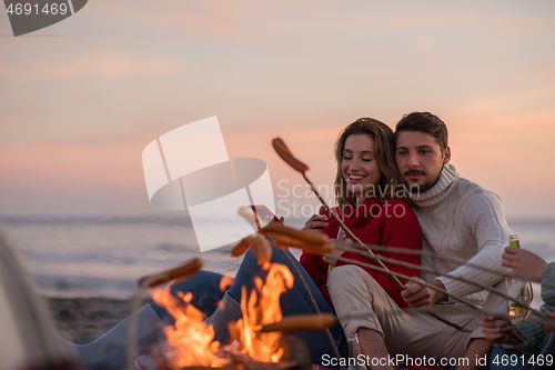 Image of Group Of Young Friends Sitting By The Fire at beach