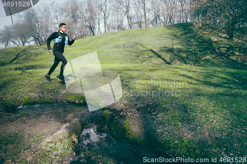 Image of Man running in a park or forest against trees background.